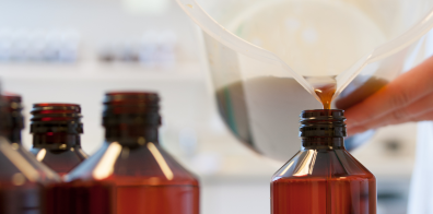 liquid from a jug being poured into a brown bottle