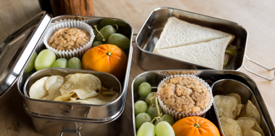 raisins, chips, sandwich, cupcake et une orange dans trois boîtes à lunch en métal 