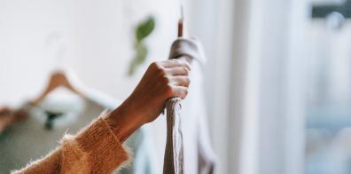 Hand holding up grey shirt on hanger