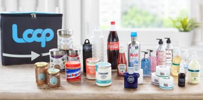 A series of food, drink and household items in reusable containers with a branded Loop box in the background