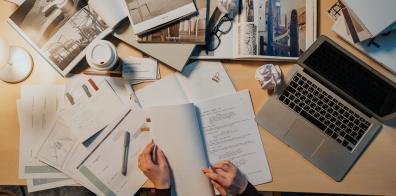 Documents, magazines and open laptop on desk