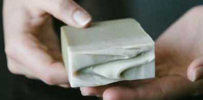 Hands holding grey soap bar